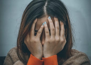 woman covering her face with both hands