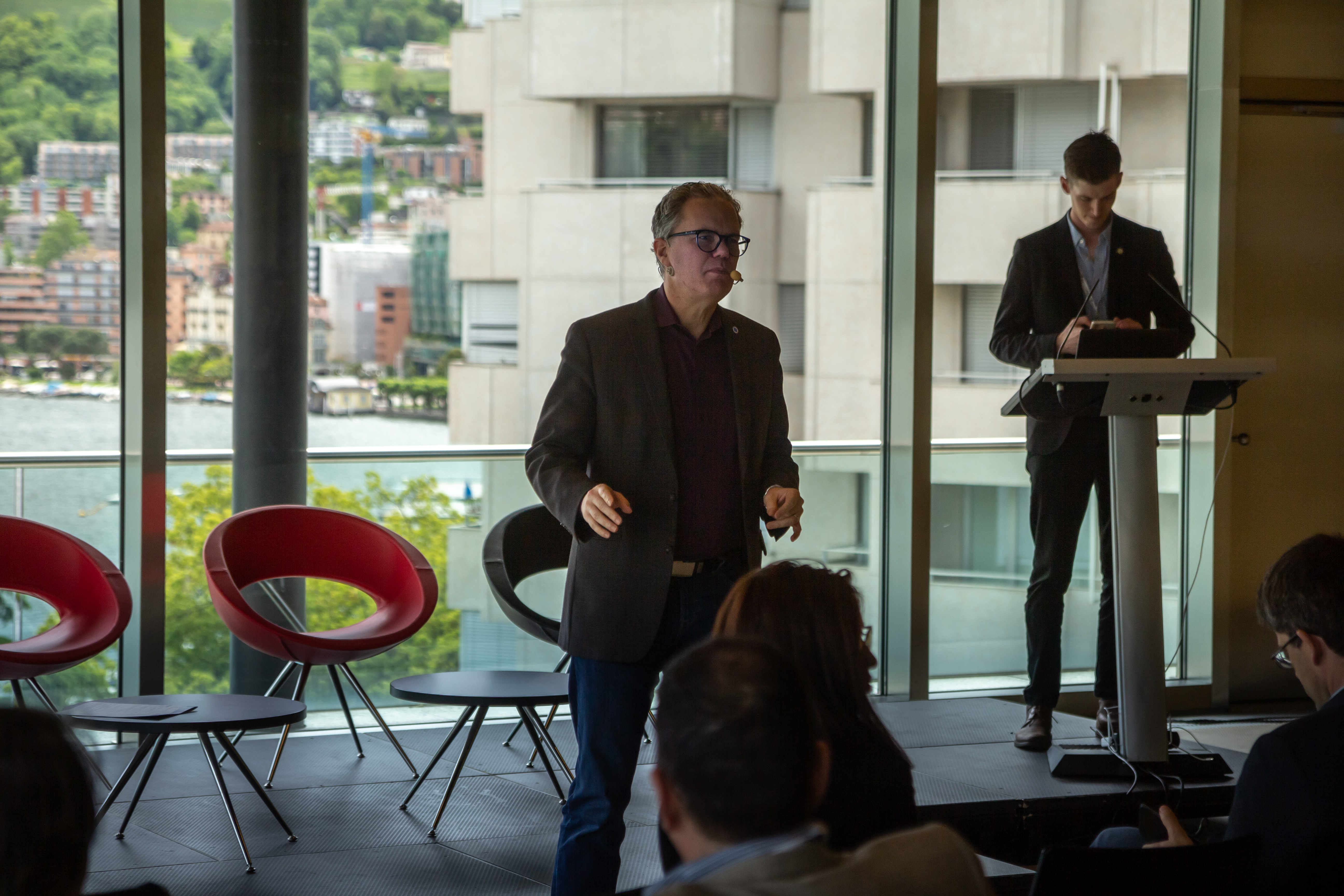 Thomas Cox speaking from a stage in Lugano, Switzerland.